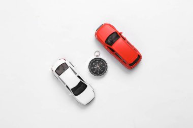 Beyaz arka planda pusulası olan oyuncak arabalar. Seyahat konsepti. Üst görünüm