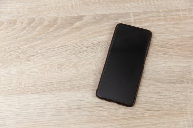 Ahşap bir masada akıllı telefon. Üst görünüm