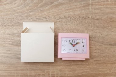 Tahta masa üzerinde yeni çalar saat olan boş beyaz kutu. Üst görünüm