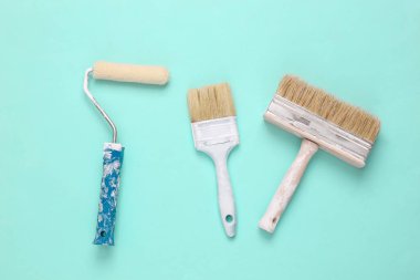 Açık mavi arka planda boya fırçaları ve silindirler. Onarım sembolü