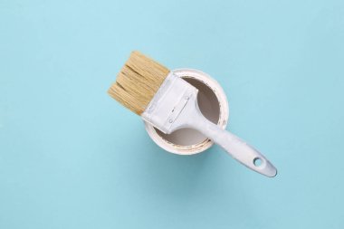 Mavi arka planda bir kutu beyaz boya ile boya fırçası
