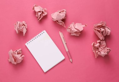 Pembe arka planda buruşuk kağıt topları olan defter.