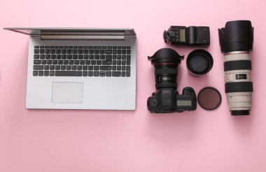 Pembe arka planda dizüstü bilgisayarı olan profesyonel fotoğraf ekipmanları (lensli kamera). Üst Manzara. Düz yatıyordu