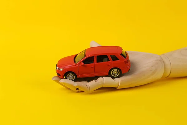 Mão Madeira Segurando Modelo Carro Brinquedo Fundo Amarelo — Fotografia de Stock