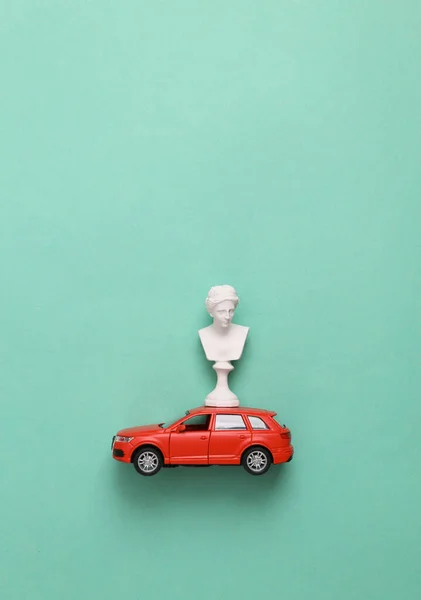 Minimalistic still life. Venus Bust on car model, blue background