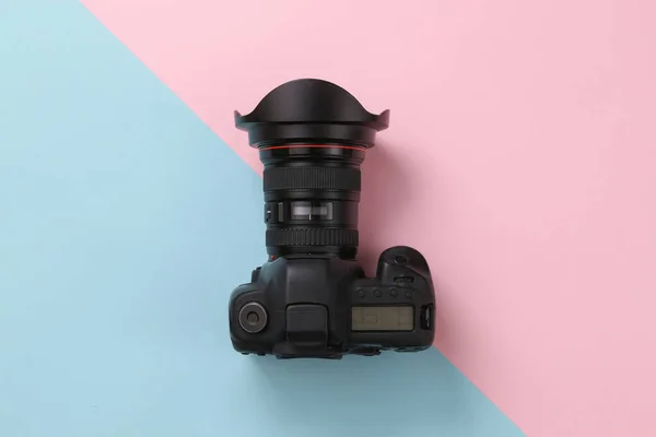Professional digital camera on blue-pink background. Top view.