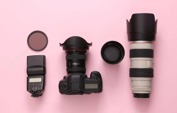 Set of professional photographic equipment (camera with lenses) on a pink background