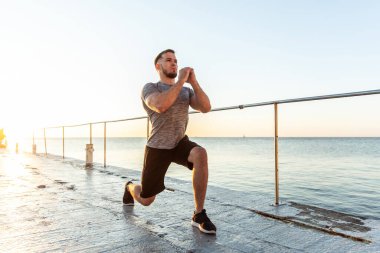 Atletik adam sabahın erken saatlerinde plajda hamleler yapıyor.