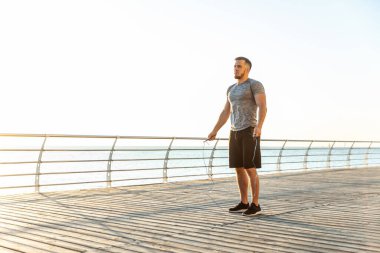 Athletic man with skipping rope on the beach in the early morning