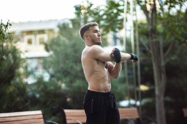 Genç atletik adam dışarıda egzersiz yapmadan önce el alıştırması yapıyor. Sağlıklı yaşam tarzı