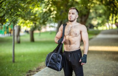 Çıplak gövdesi ve spor çantası olan genç bir sporcunun portresi.