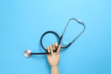Ahşap el mavi arka planda steteskop tutuyor. Tıp konsepti