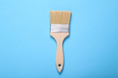 Mavi arkaplanda ahşap saplı boya fırçası