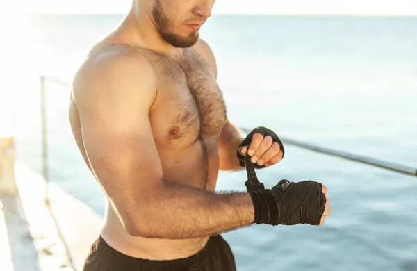 Atletický Muž Brzy Ráno Pláži Omotává Ruce Kickboxerskými Obvazy — Stock fotografie