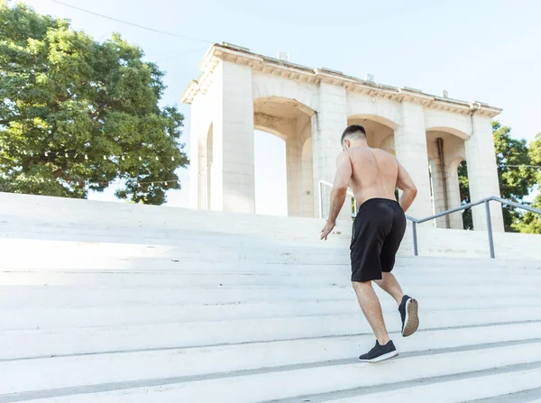 The male athlete runs up the stairs outdoors. Healthy lifestyle