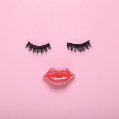 Sahte kirpikler ve pembe arka planda yüz şeklinde dudaklar. Güzellik konsepti
