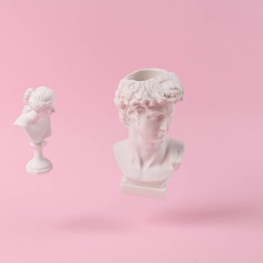 David ve Venüs 'ün pembe arka planda gölgeli antik alçı büstleri. Kavramsal patlama. Asgari natürmort
