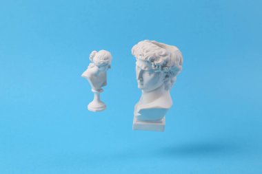 David ve Venüs 'ün mavi arka planda gölgeli antik alçı büstleri. Kavramsal patlama. Asgari natürmort