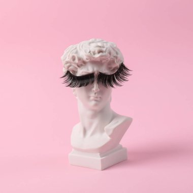 David 'in pembe arka planda takma kirpikli antika büstü. Kavramsal patlama. Asgari güzellik ve moda hayattır. Yaratıcı fikir