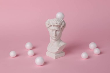 David 'in pembe arka planda beyaz topları olan antika büstü. Kavramsal patlama. Minimal natürmort. Yaratıcı fikir