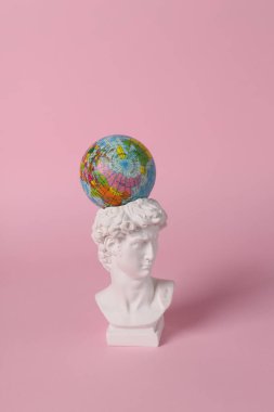 Antika David pembe arka planda küre ile büstü. Kavramsal patlama. Minimal natürmort. Yaratıcı seyahat düzeni