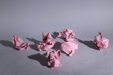 Gri arkaplanda pembeleşmiş kağıt toplar ve gölgeler.
