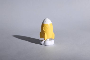 Oyuncak sarı uzay mekiği ya da gölgeli gri arka planda roket. Minimalizm, kavramsal pop, yeni fikir veya başlangıç