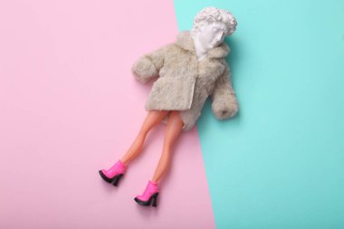 David 'in Kafası' nda bebek kürkü manto ve mavi-pembe arka planda bacakları var. Yaratıcı moda düzeni. Minimal natürmort. Düz yatıyordu. Üst görünüm