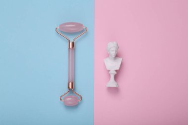 Minimum güzellik hala hayattadır. Pembe arka planda yüz masajı yapan Venüs büstü. Üst görünüm