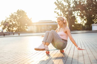 Şirin bir kız kaykayın üzerinde otururken