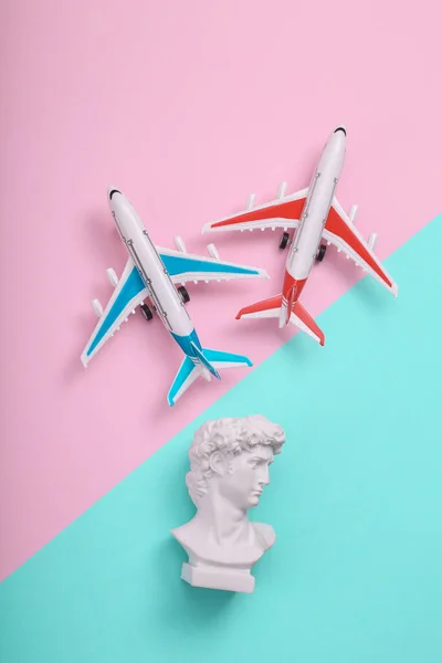 Air planes with David bust on pink blue background. Creative layout. Minimal travel still life. Flat lay. Top view