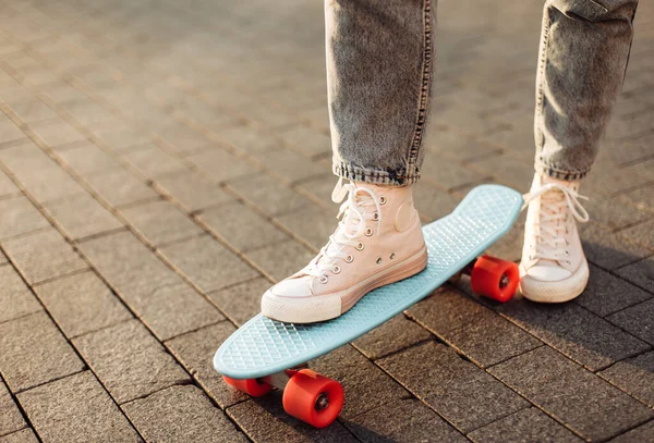 Kotlu ve spor ayakkabılı kadın bacakları kaykaya biniyor.