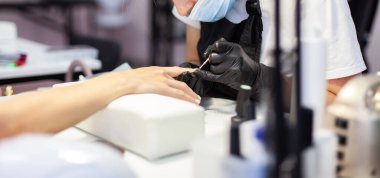 Manikürcü müşterinin tırnaklarıyla çalışıyor. Tırnak bakımı, manikür.