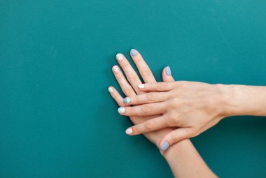 Beautiful female hands with pastel color manicure on green background