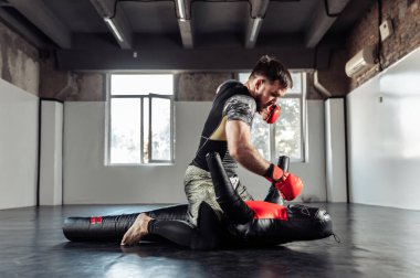 MMA dövüşçüsü spor salonundaki bir mankeni yumrukluyor.