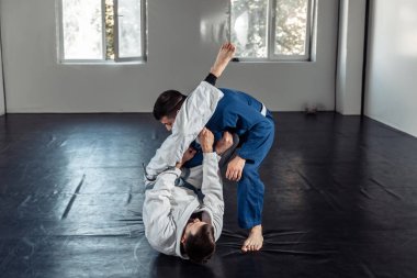 İki dövüşçü, kimono antrenmanında antrenman partnerleri tutuş ve spor salonuna atıyorlar.