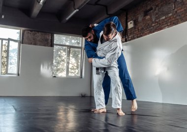İki dövüşçü, kimono antrenmanında antrenman partnerleri tutuş ve spor salonuna atıyorlar.