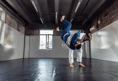 İki dövüşçü, kimono antrenmanında antrenman partnerleri tutuş ve spor salonuna atıyorlar.