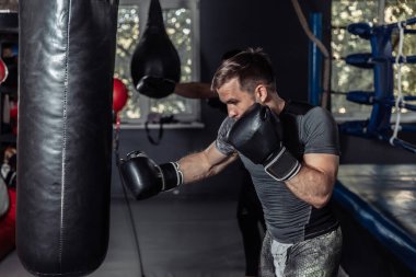 Athlete boxer trains punches in boxing gloves with a punching bag