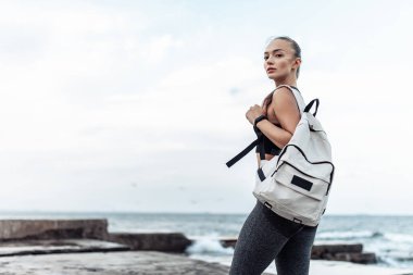 Portrait of young fit woman in sportswear on urban beach