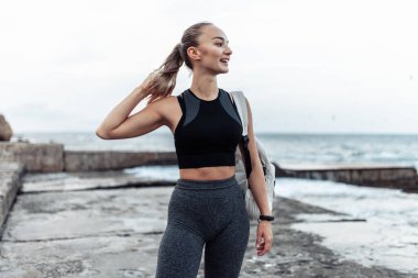 Portrait of young fit woman in sportswear on urban beach