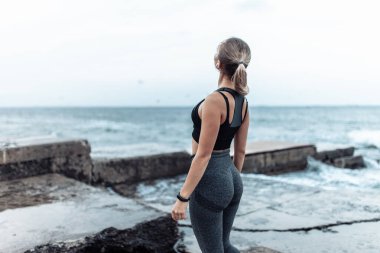 Back view of fitneg woman with perfect body on urban beach