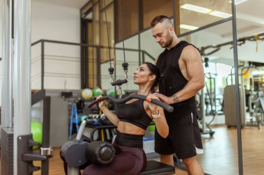 Young fit woman training muscles with personal trainer man in the gym