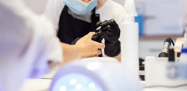 Manicurist paints with nail polish the nails of a woman\'s clint in nail salon. The working process