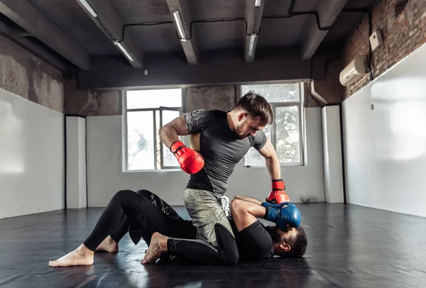 ジムでキックボクシングの手袋で戦う2人のスパーリング戦闘機 — ストック写真