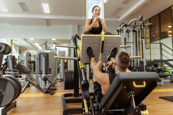 Strong Man Doing Leg Press Exercise Machine Woman Sitting Gym — Foto Stock