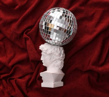 Kırmızı buruşuk ipek arka planda ayna disko topu ile David alçı büst