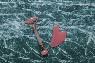 Mermer zemin üzerinde Guasha taşı olan yeşim masaj silindiri.