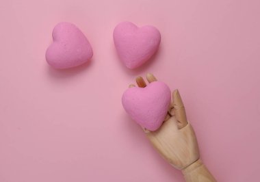 Pembe arka planda kalpleri tutan eller. Aşk konsepti. Üst görünüm