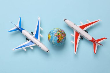 Mavi arka planda küresi olan oyuncak model uçaklar. Seyahat konsepti. Düz yatış, üst görünüm